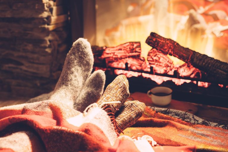 two pairs of feet with socks on in front of a fireplace in the background