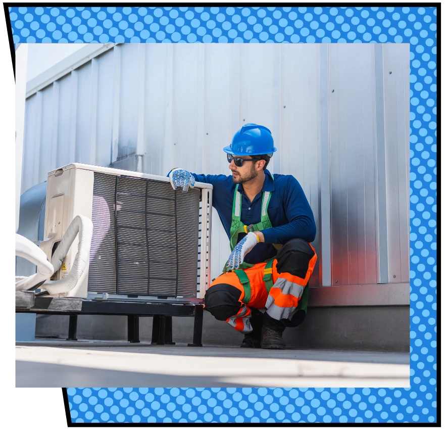 A technician in safety gear, blue helmet, and orange safety pants inspects an HVAC unit on a roof, conveying a sense of focus and expertise.