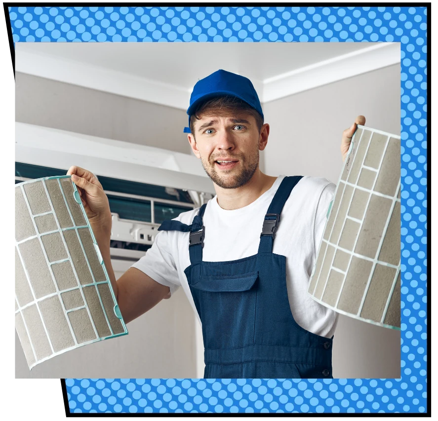 Man in blue cap and overalls holds two dirty air filters, standing near an open air conditioner. He looks surprised. Blue polka dot border.
